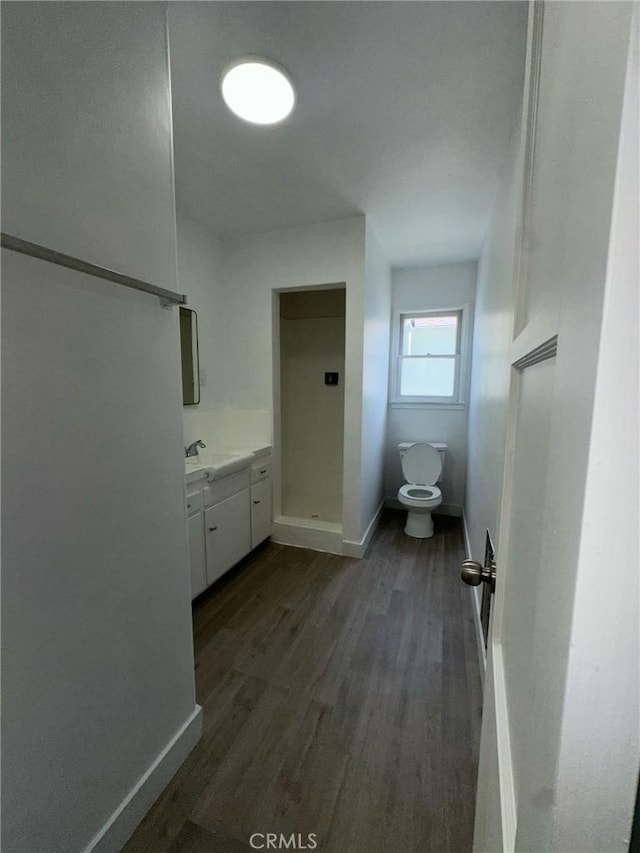 bathroom featuring toilet, wood finished floors, and baseboards