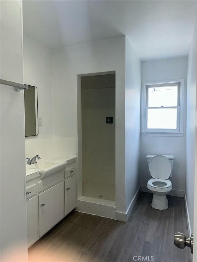 bathroom featuring baseboards, a shower stall, vanity, and wood finished floors