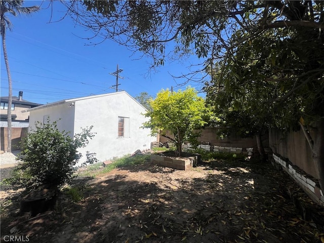 view of side of home featuring a fenced backyard, stucco siding, and a vegetable garden