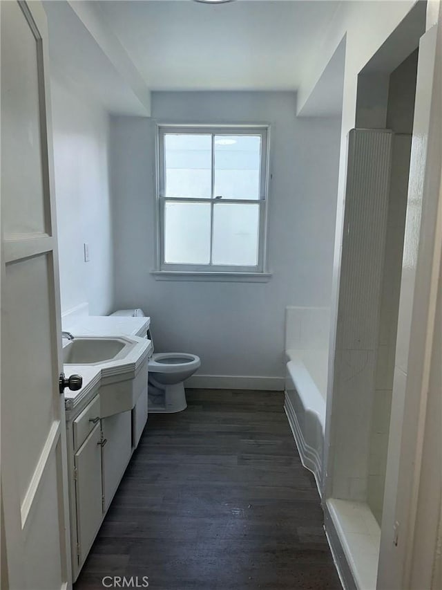 bathroom with vanity, baseboards, walk in shower, toilet, and wood finished floors