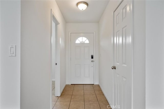 doorway with light tile patterned floors and baseboards