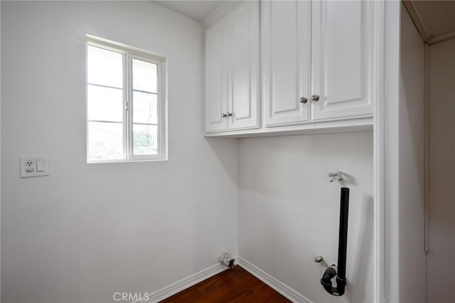 clothes washing area with hookup for a gas dryer, dark wood-style floors, baseboards, and cabinet space