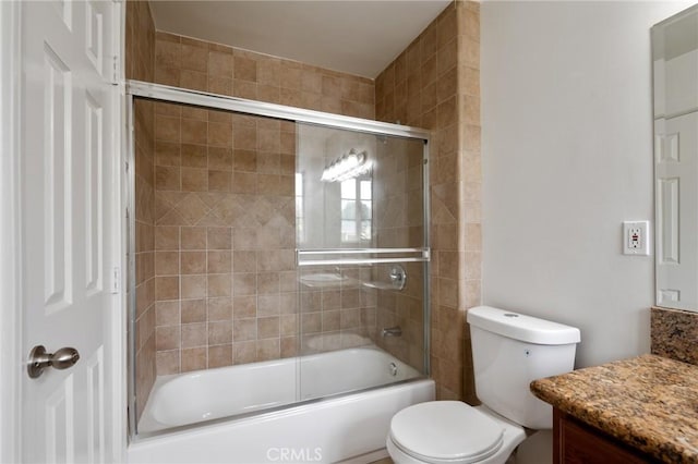 bathroom with enclosed tub / shower combo, vanity, and toilet
