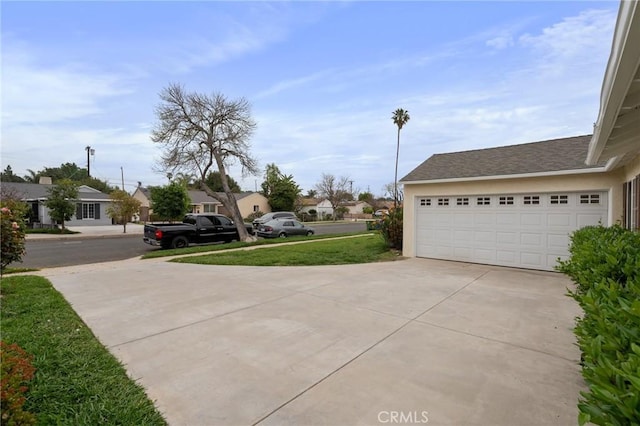 view of yard featuring a residential view, a garage, and concrete driveway