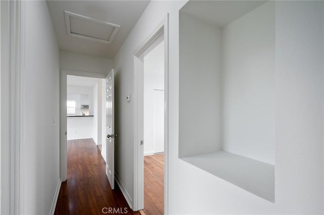 hall with baseboards, attic access, and wood finished floors