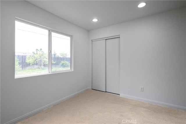 unfurnished bedroom featuring a closet, recessed lighting, carpet flooring, and baseboards