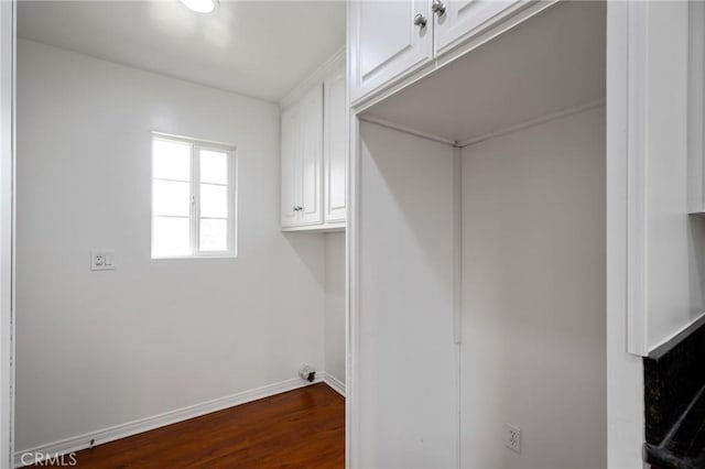 laundry room featuring baseboards, cabinet space, and dark wood finished floors