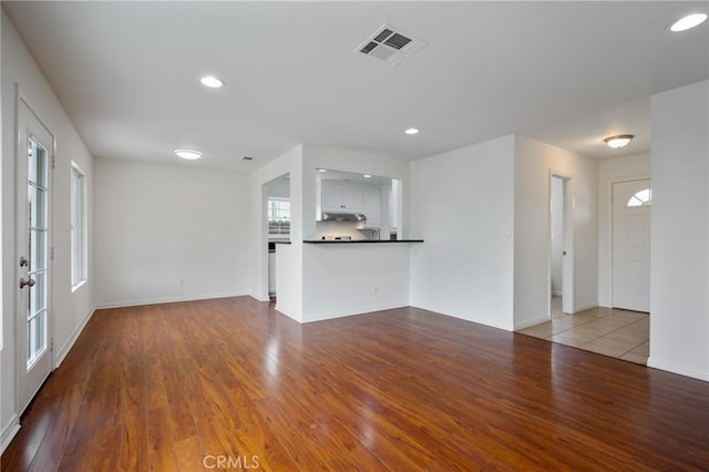 unfurnished living room with recessed lighting, visible vents, baseboards, and wood finished floors