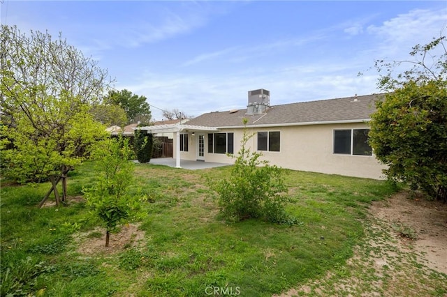 back of property with a pergola, a patio area, stucco siding, and a lawn