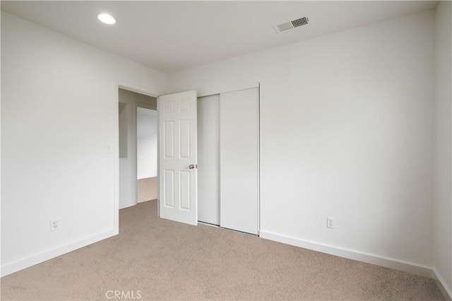 unfurnished bedroom featuring a closet, visible vents, recessed lighting, carpet floors, and baseboards