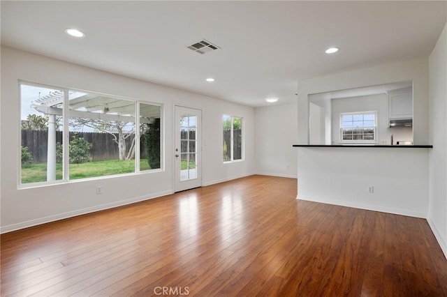 unfurnished living room featuring visible vents, baseboards, and wood finished floors