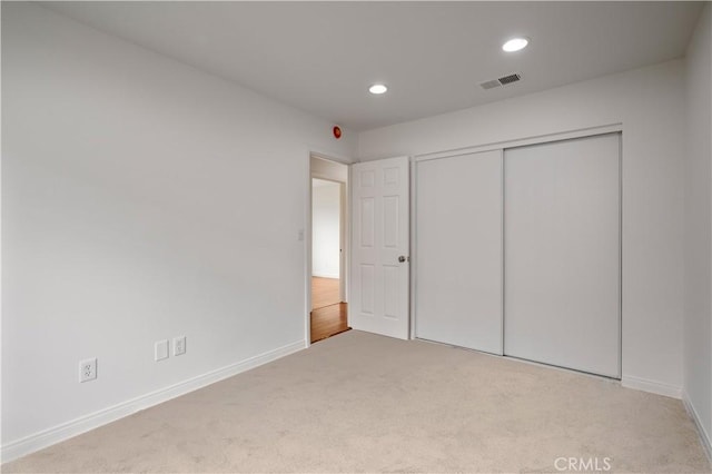 unfurnished bedroom with a closet, baseboards, recessed lighting, carpet flooring, and visible vents