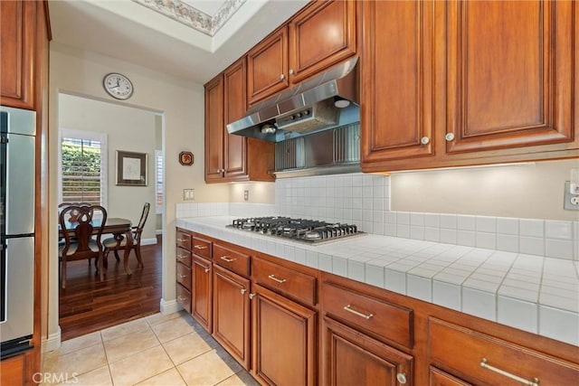 28311 Harvest View Ln, Lake Forest, CA 92679 - kitchen with stainless steel appliances, under cabinet range hood, tile counters, tasteful backsplash, and light tile patterned floors