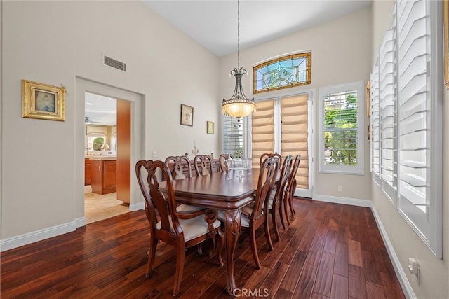 dining space with wood-type flooring, baseboards, and a high ceiling