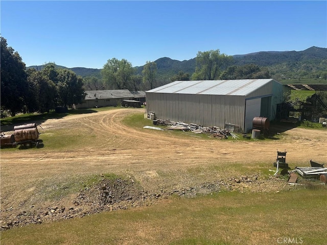 exterior space featuring an outbuilding, a mountain view, and dirt driveway