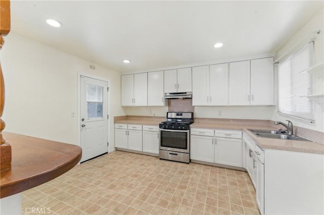 1114 Stovall Ave, La Puente, CA 91745 - kitchen with a sink, stainless steel gas range, white cabinetry, light countertops, and under cabinet range hood