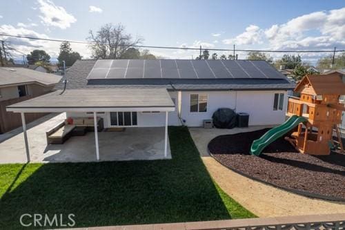 45522 Andale Ave, Lancaster, CA 93535 - rear view of house featuring a patio, solar panels, a playground, and a lawn