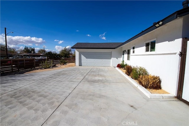 45522 Andale Ave, Lancaster, CA 93535 - view of home's exterior featuring driveway, an attached garage, stucco siding, and fence