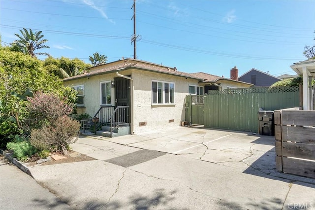 view of front of home featuring stucco siding, fence, a gate, and crawl space