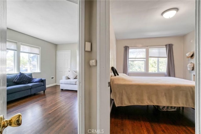bedroom with dark wood-style floors, multiple windows, and baseboards