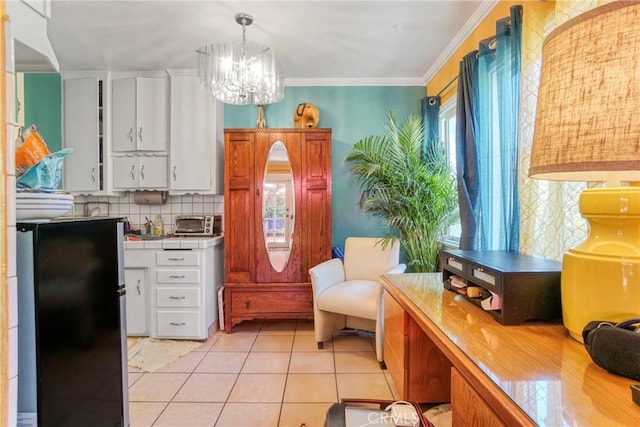 kitchen with tile counters, white cabinets, freestanding refrigerator, and a notable chandelier