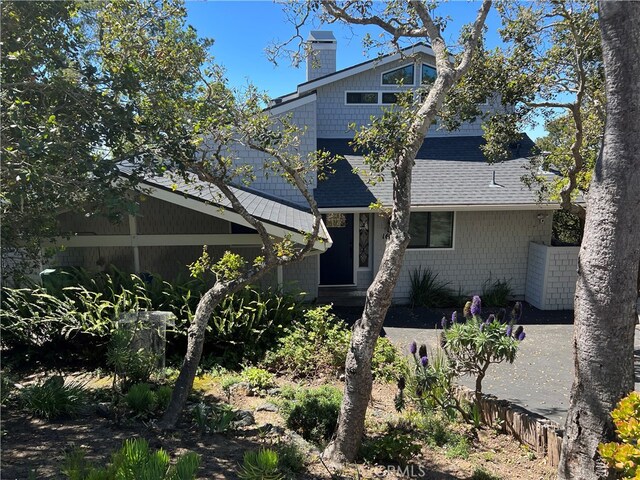 exterior space with a chimney and a shingled roof