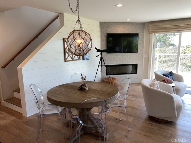 dining room featuring stairway, a tiled fireplace, recessed lighting, and wood finished floors