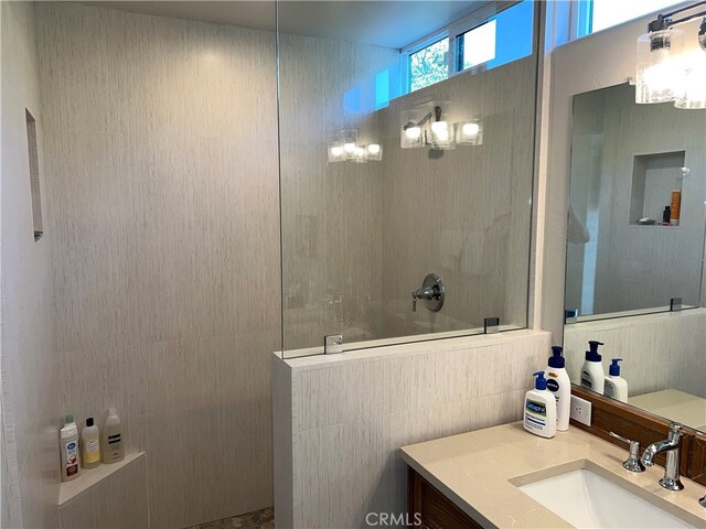 bathroom featuring vanity, tile walls, and walk in shower