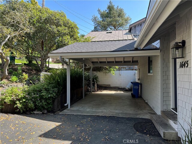 view of parking featuring an attached carport, entry steps, and aphalt driveway