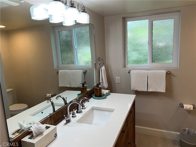 bathroom featuring baseboards, vanity, toilet, and a chandelier