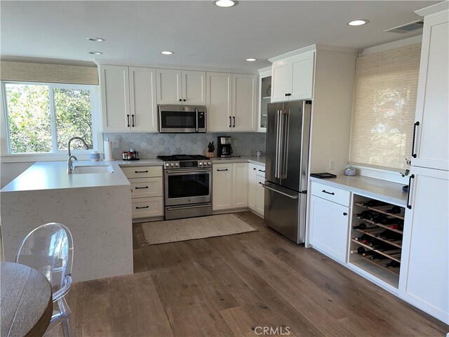 kitchen featuring dark wood-style flooring, light countertops, white cabinetry, a sink, and appliances with stainless steel finishes