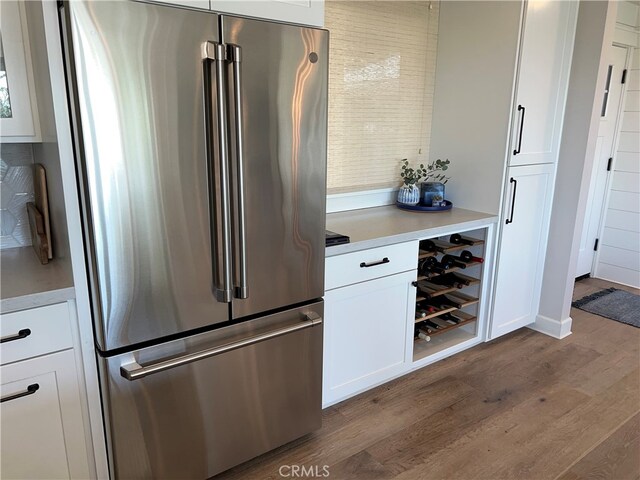 kitchen featuring high end fridge, light countertops, dark wood finished floors, and white cabinetry