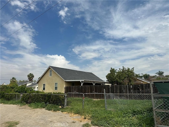 view of side of home featuring fence and stucco siding