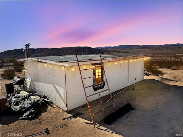 property exterior at dusk featuring a mountain view