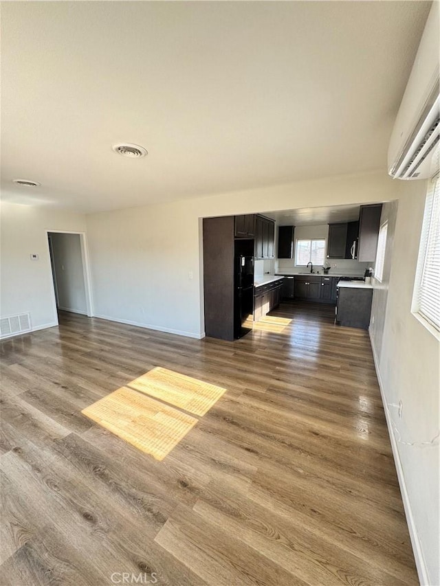 26659 6th St, Highland, CA 92346 - unfurnished living room featuring a wall unit AC, wood finished floors, and baseboards