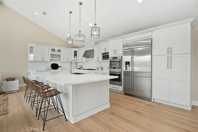 625 Calle Miguel, San Clemente, CA 92672 - kitchen featuring appliances with stainless steel finishes, wall chimney range hood, backsplash, white cabinets, and high vaulted ceiling