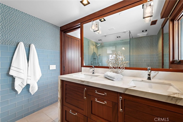 bathroom with a sink, tile walls, a shower stall, and tile patterned floors