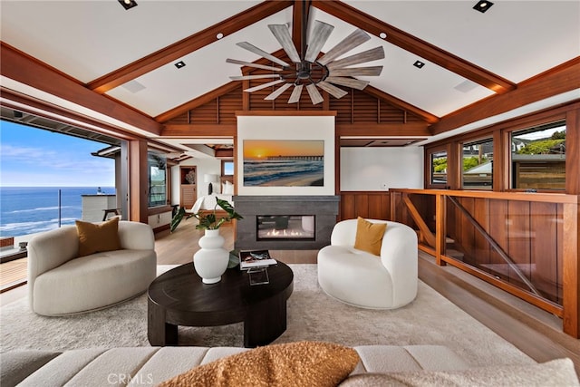 living room with wooden walls, plenty of natural light, beamed ceiling, and wood finished floors