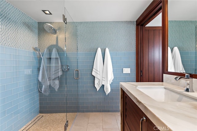 bathroom featuring vanity, tile walls, tile patterned flooring, and a stall shower
