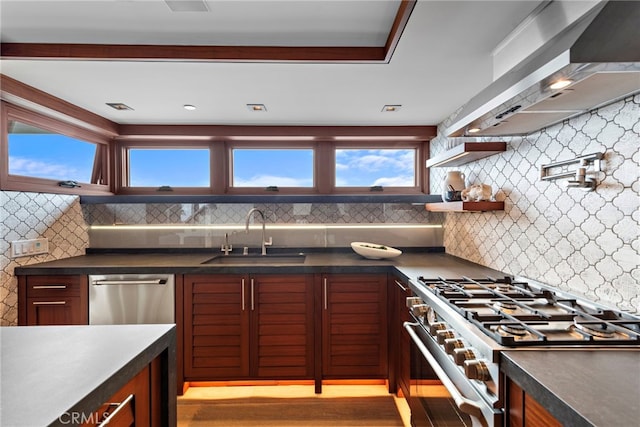 kitchen featuring a sink, dark countertops, stainless steel appliances, and wall chimney exhaust hood