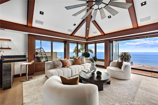 living room featuring a water view, beamed ceiling, a ceiling fan, and wood finished floors