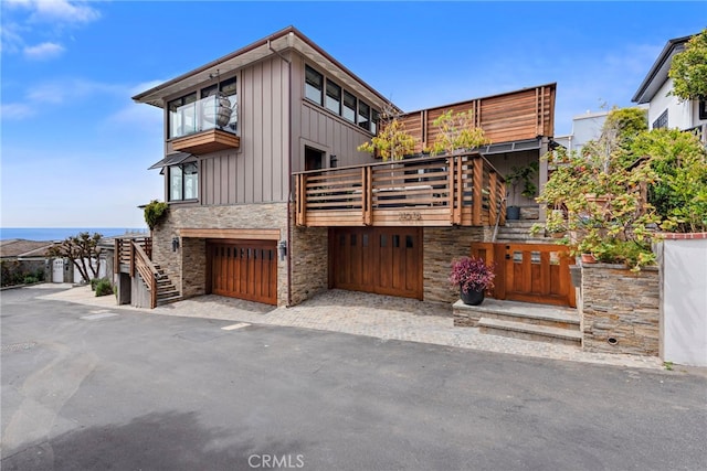 view of front of property with a balcony, stairs, board and batten siding, and stone siding