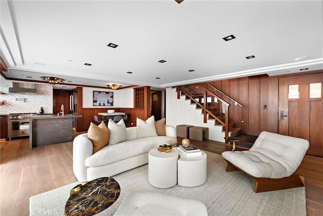 living room with stairway, wooden walls, and light wood-style flooring