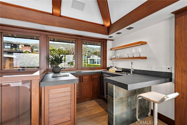 bar featuring wood finished floors, indoor wet bar, beverage cooler, vaulted ceiling with beams, and a sink