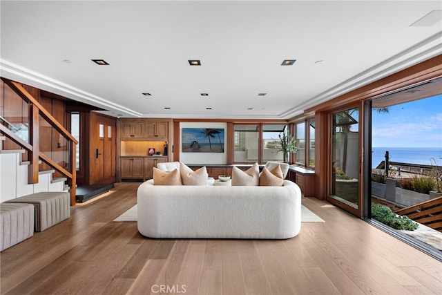 living area featuring stairs, a water view, and wood finished floors