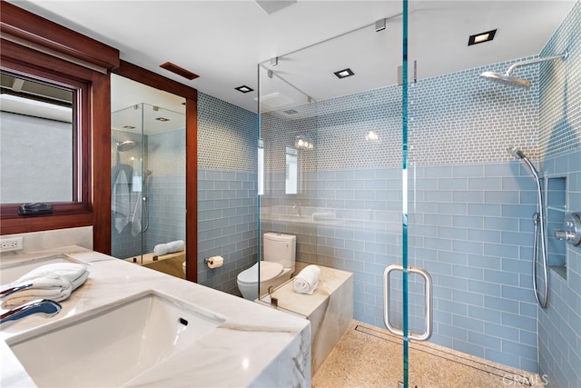 full bathroom featuring vanity, toilet, tile walls, and a stall shower