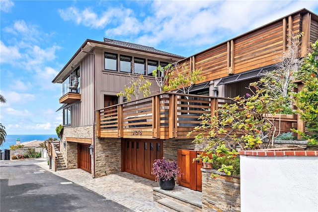 exterior space featuring driveway, a balcony, stone siding, and a garage