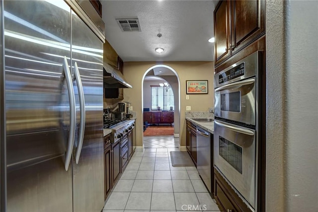 4805 Bellflower Ave Unit 205, North Hollywood, CA 91601 - kitchen featuring arched walkways, light tile patterned flooring, visible vents, under cabinet range hood, and appliances with stainless steel finishes