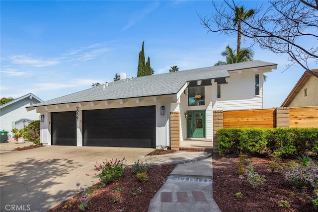 view of front of property with driveway, fence, a shingled roof, and a garage