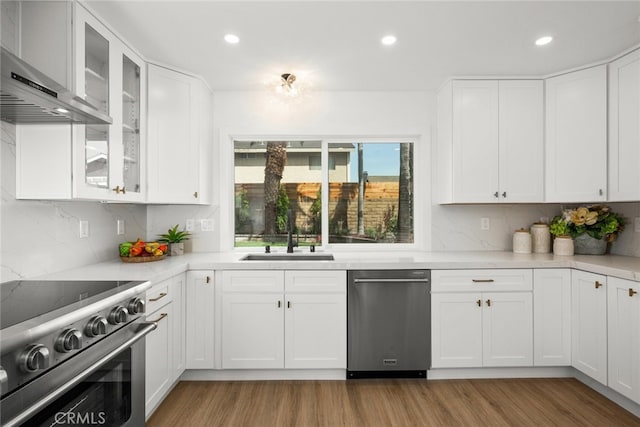 kitchen featuring decorative backsplash, a sink, appliances with stainless steel finishes, and wall chimney range hood